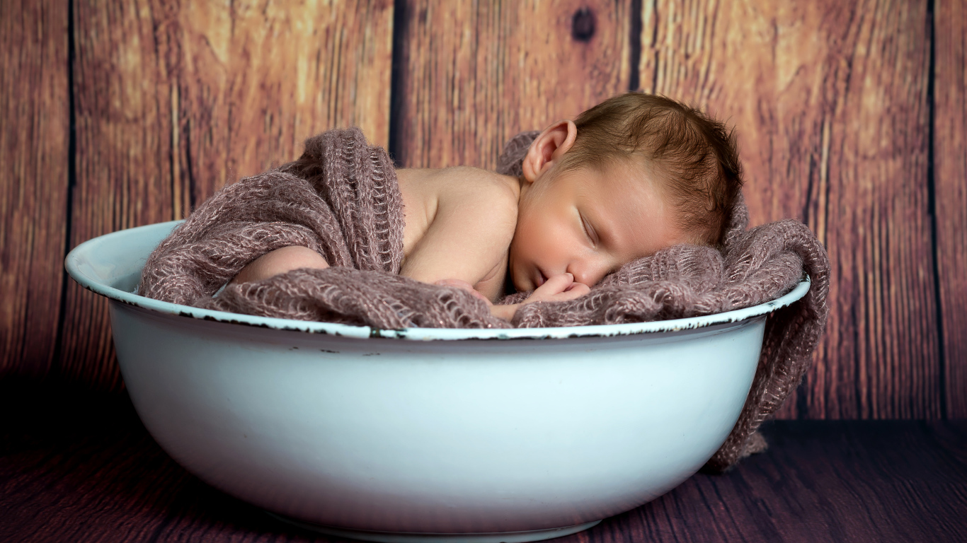 Новорожденный ребенок спит в белой миске