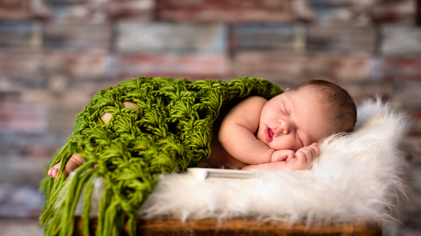 Спящий младенец под зеленым вязаным пледом