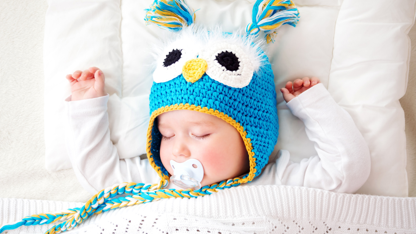 Спящий ребенок в забавной вязаной шапке
