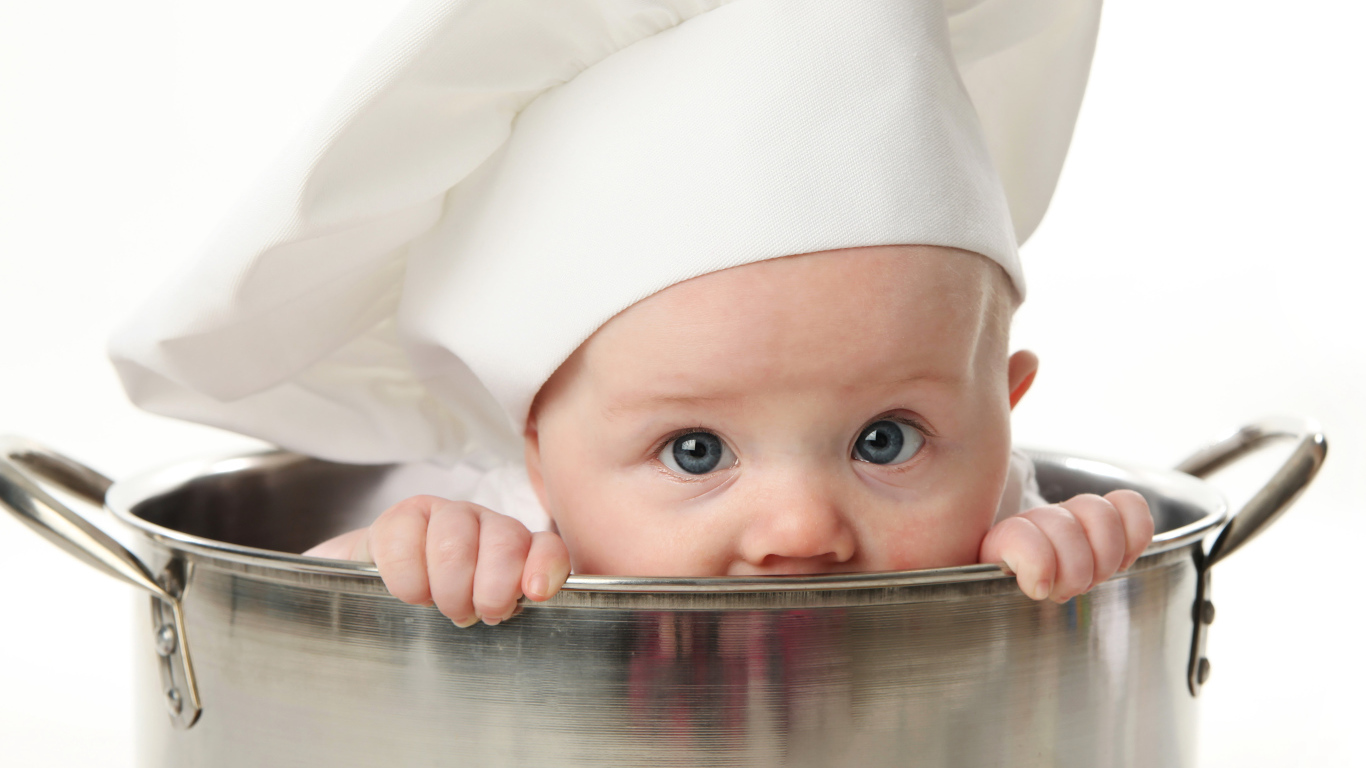 Маленький ребенок сидит в большой железной кастрюле