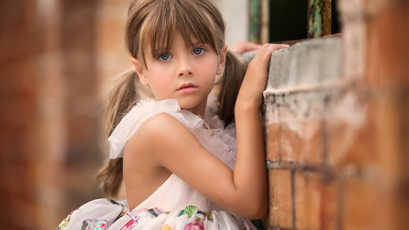 Милая девочка с серьезным взглядом стоит у стены