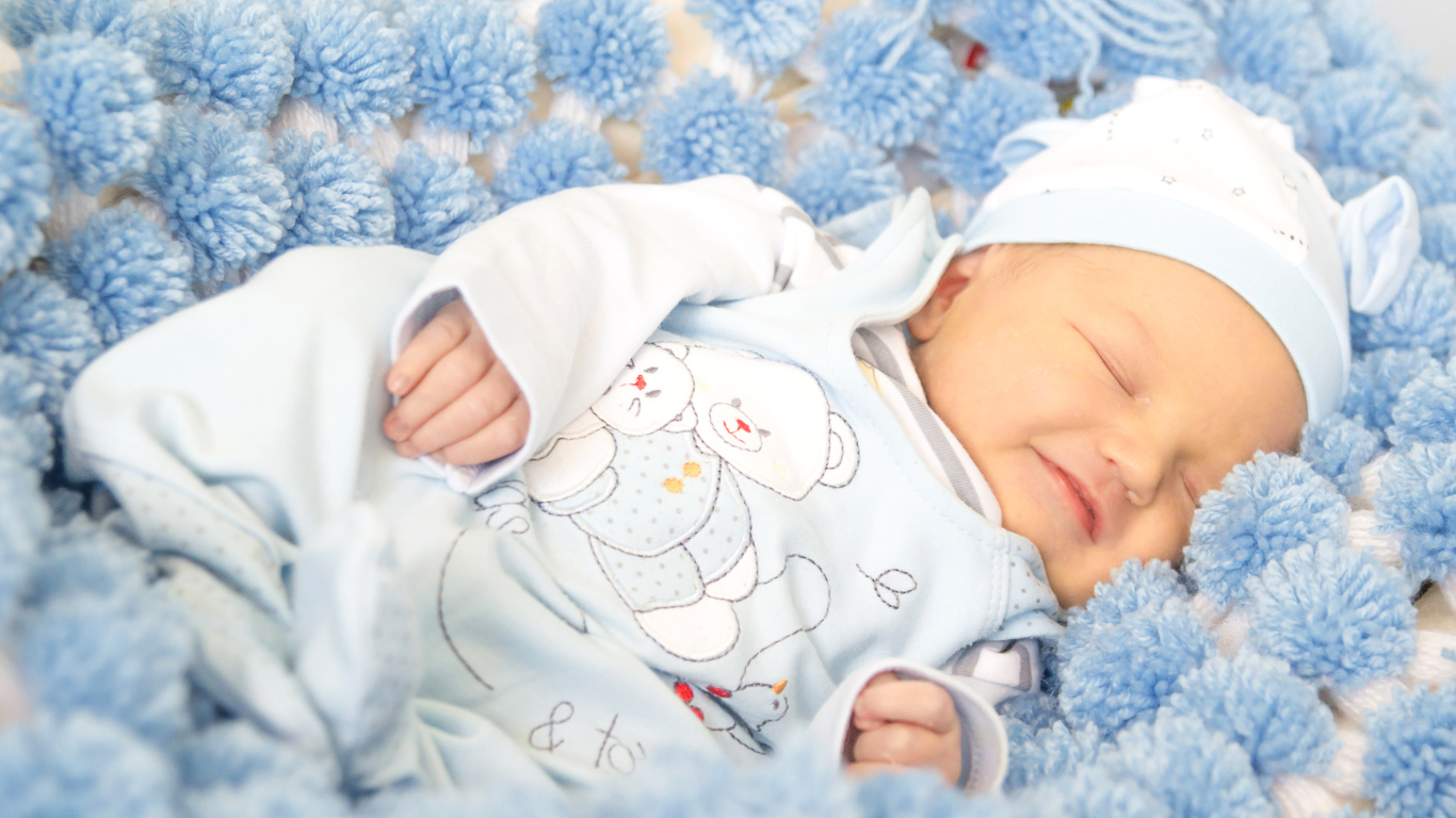 Младенец мальчик улыбается во сне