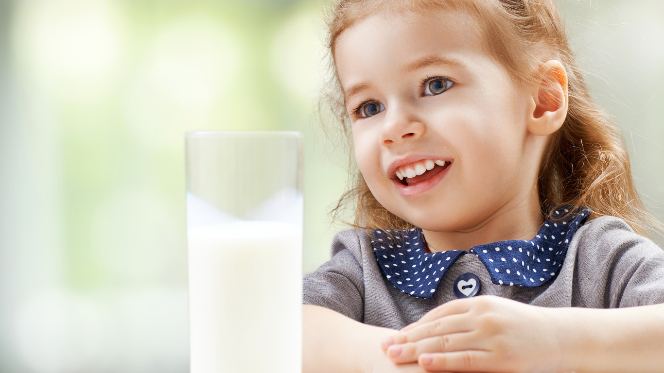 Красивая кареглазая девочка со стаканом молока