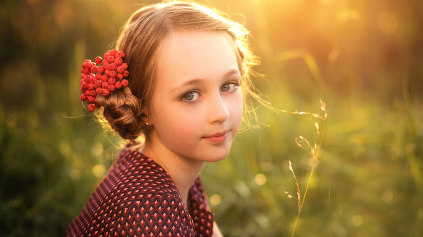 Красивая маленькая девочка с ягодами калины в волосах