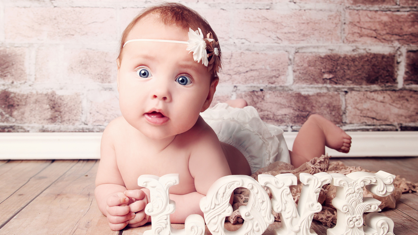 Грудной ребенок с надписью любовь на фоне кирпичной стены