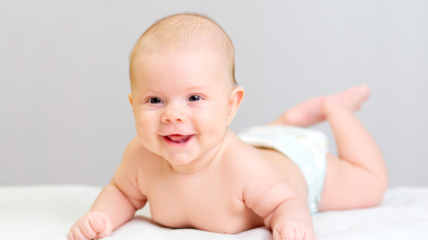 Милый улыбающийся ребенок на сером фоне