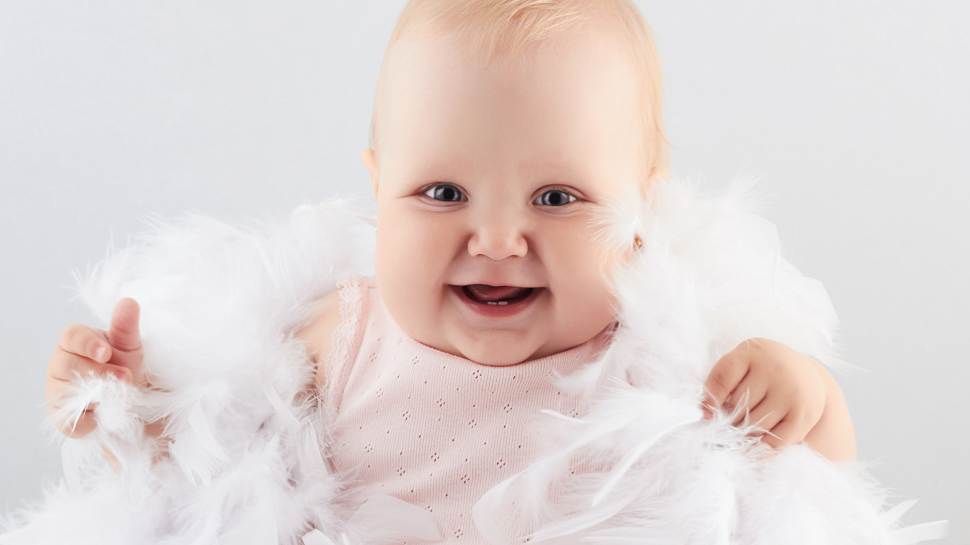 Забавная улыбающаяся маленькая девочка в белых перьях