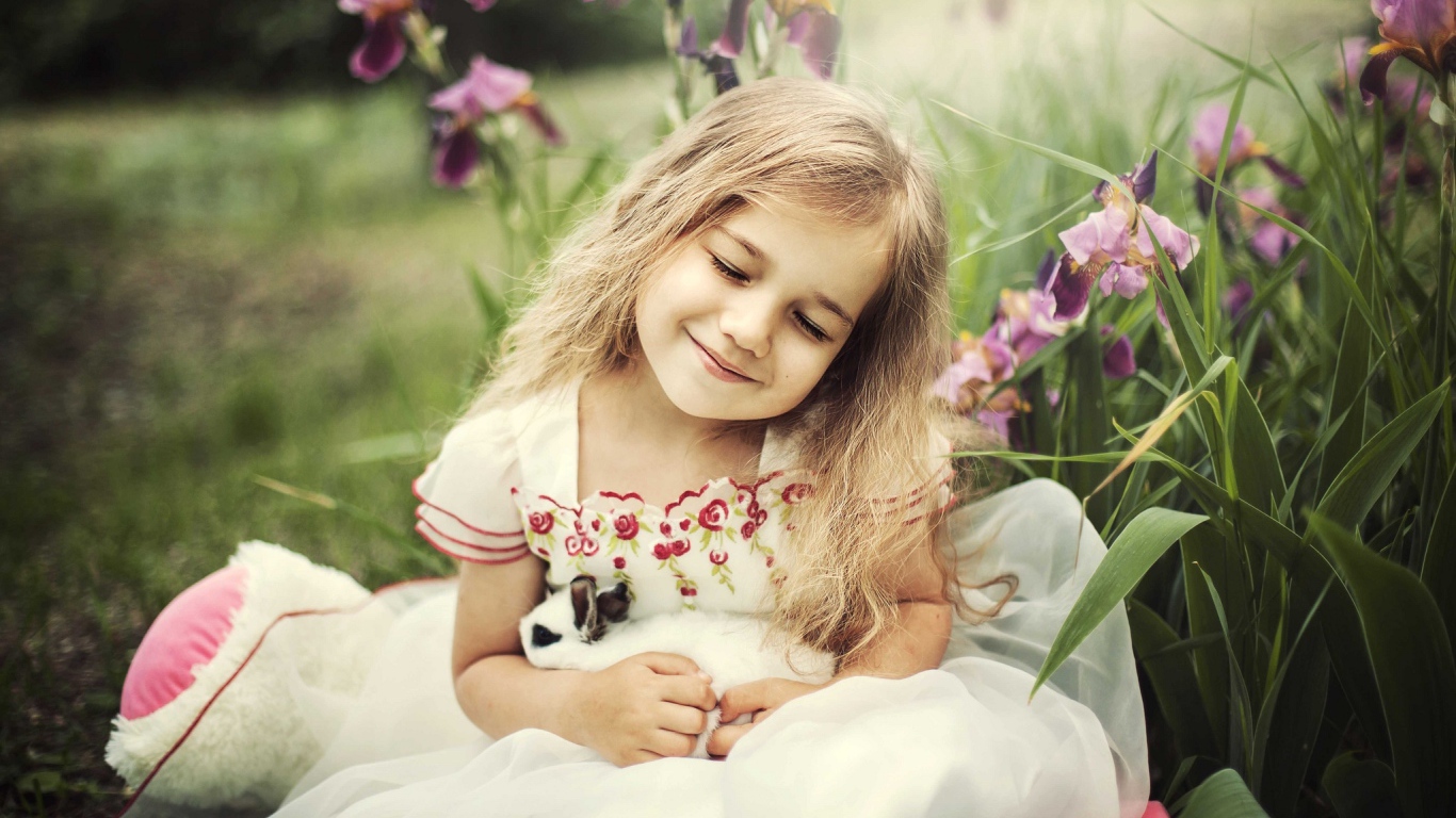 Маленькая девочка блондинка держит в руках кролика