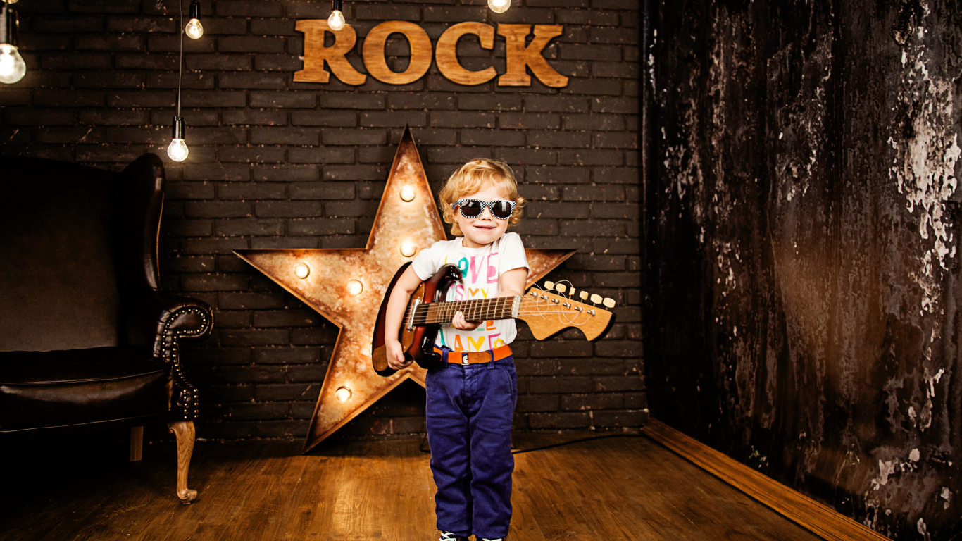 Маленький мальчик в модных очках с гитарой