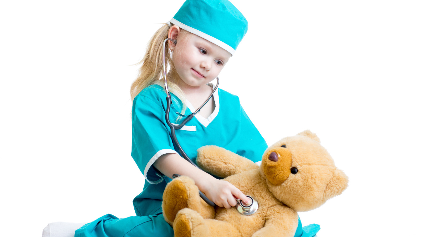 Маленькая девочка в костюме врача лечит плюшевого медвежонка