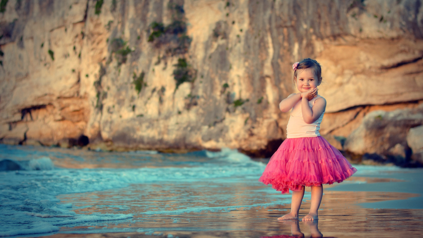Маленькая девочка в красивой розовой юбке на пляже