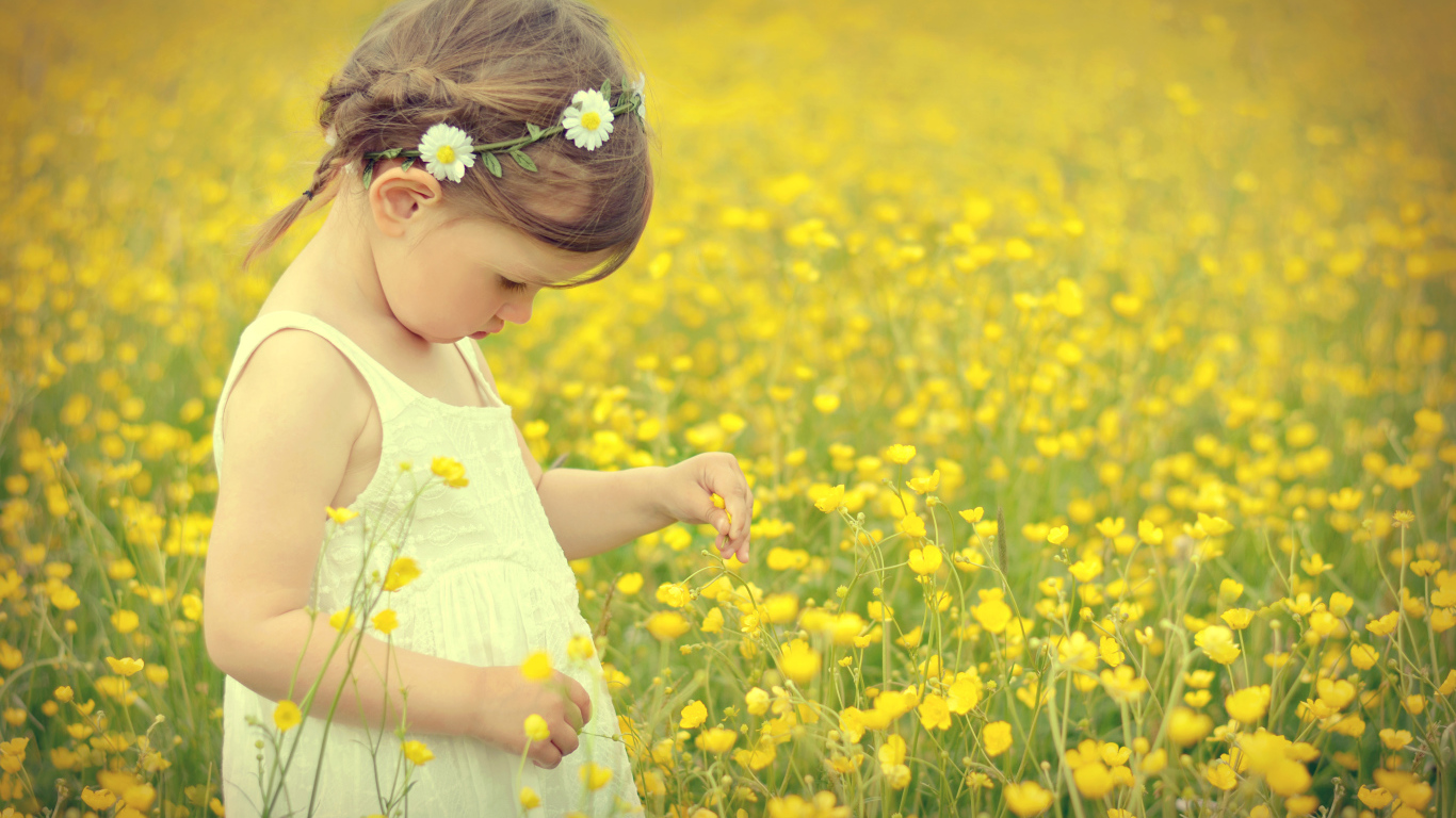 Маленькая девочка в белом платье на лугу с желтыми цветами
