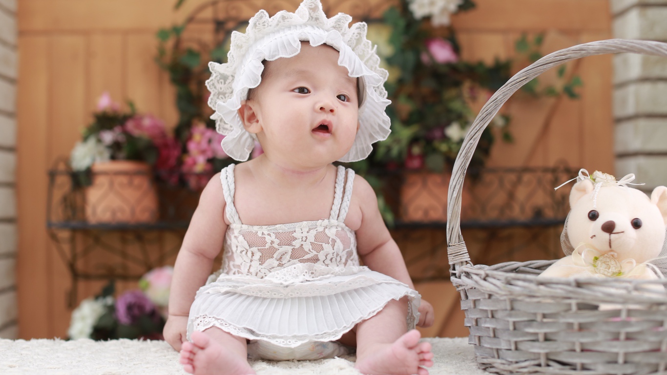 Маленькая девочка в белом платье с медвежонком в корзине