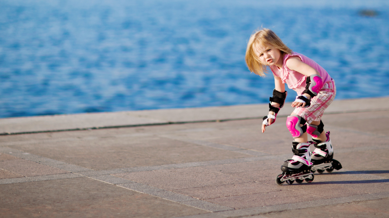 Маленькая девочка катается на роликах на побережье