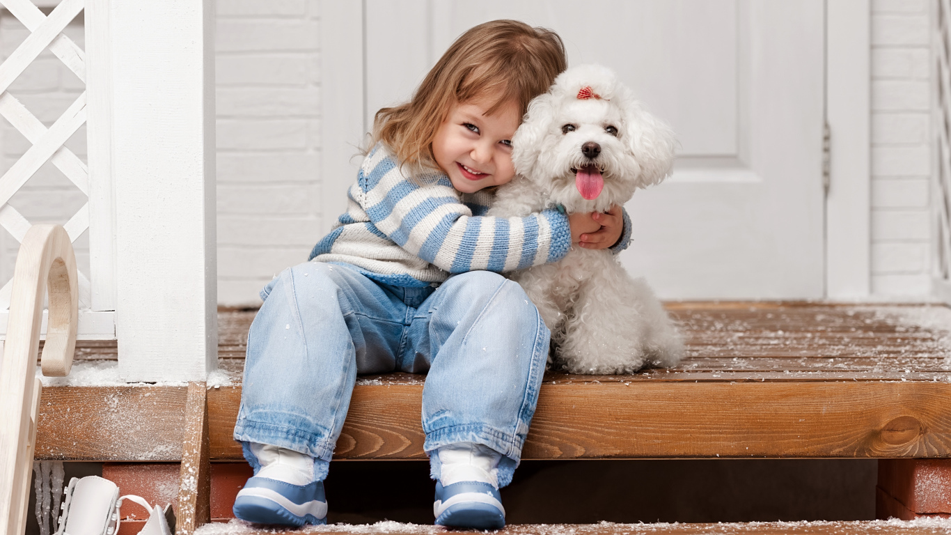 Маленькая улыбающаяся девочка сидит с белым пуделем на ступеньках