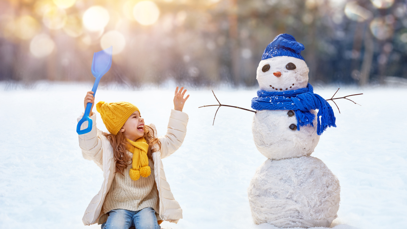 Маленькая улыбающаяся девочка со снеговиком зимой
