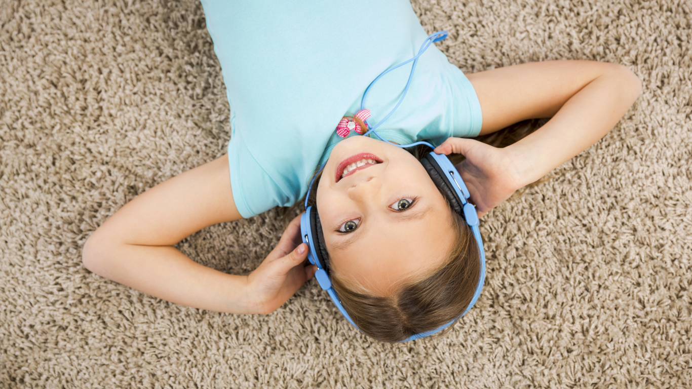 Улыбающаяся девочка в больших голубых наушниках