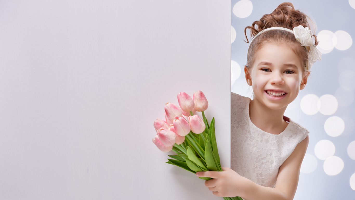 Улыбающаяся маленькая девочка с букетом розовых тюльпанов