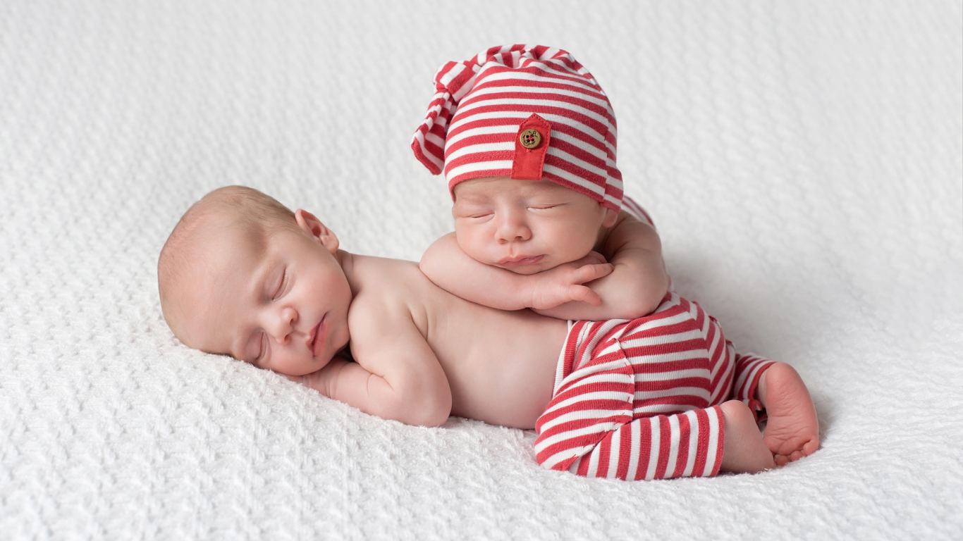 Два милых спящих младенца в полосатых костюмах