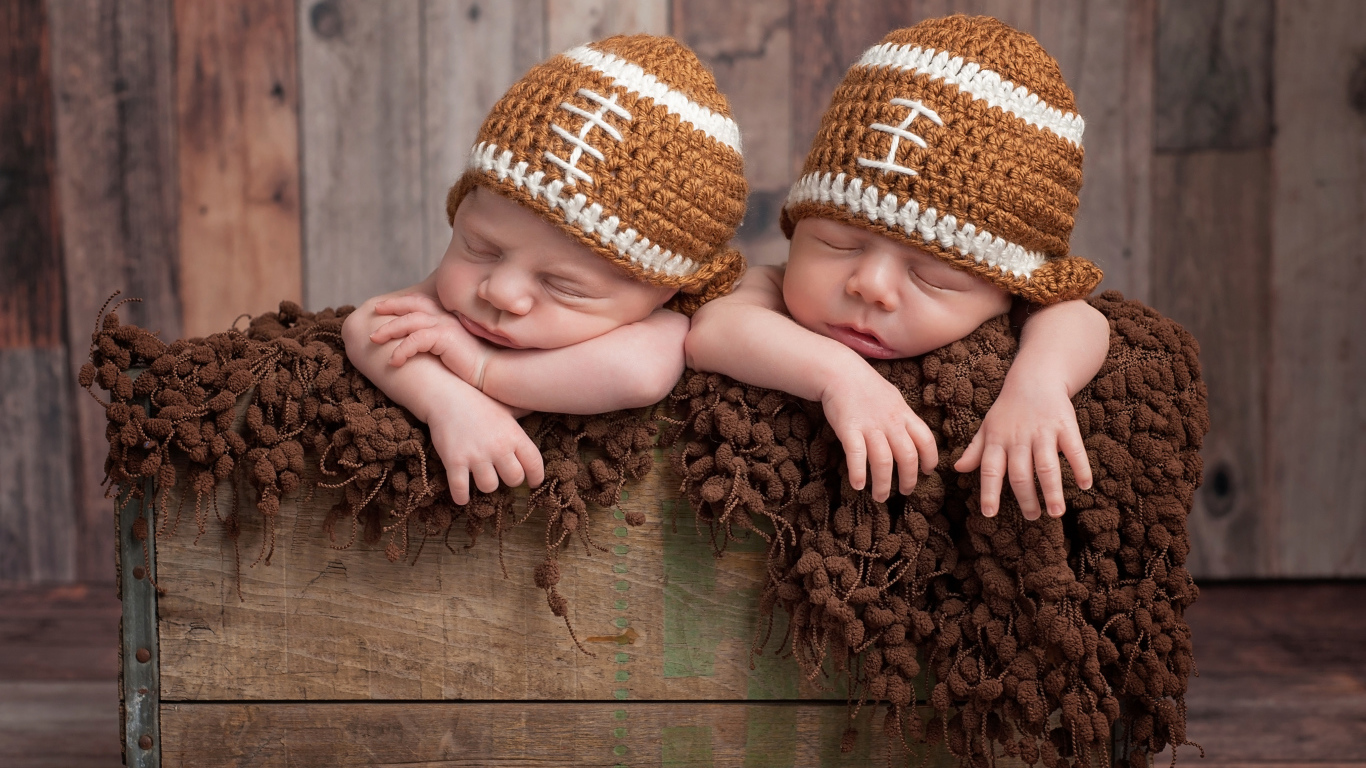 Два милых спящих малыша в забавных вязаных шапках