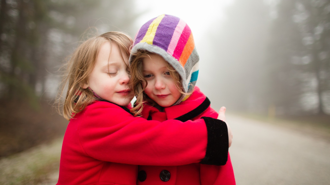Две маленькие девочки обнимают друг друга 