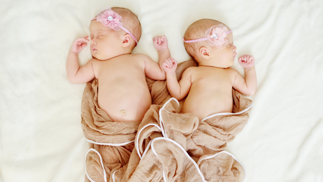 Два спящих младенца с розовыми цветами на голове