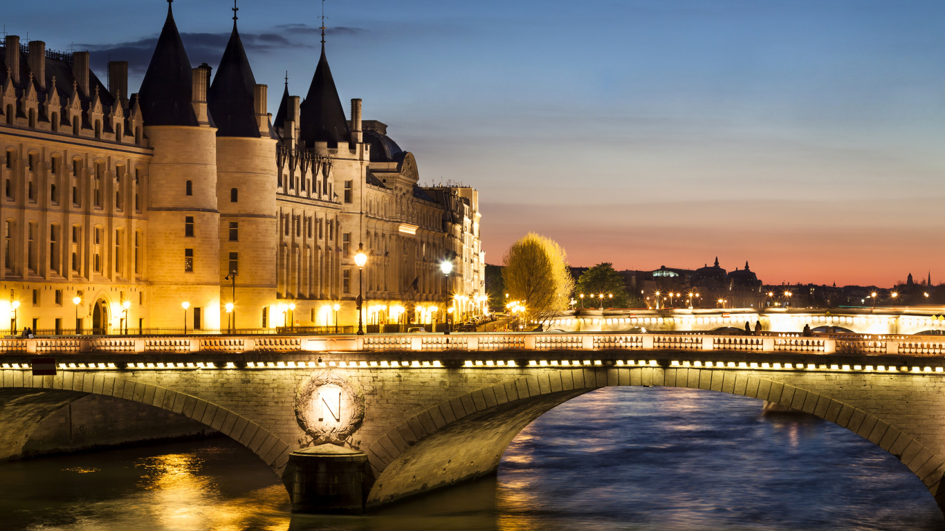Мост в свете ночных фонарей у бывшего королевского замка Консьержери, Париж. Франция 