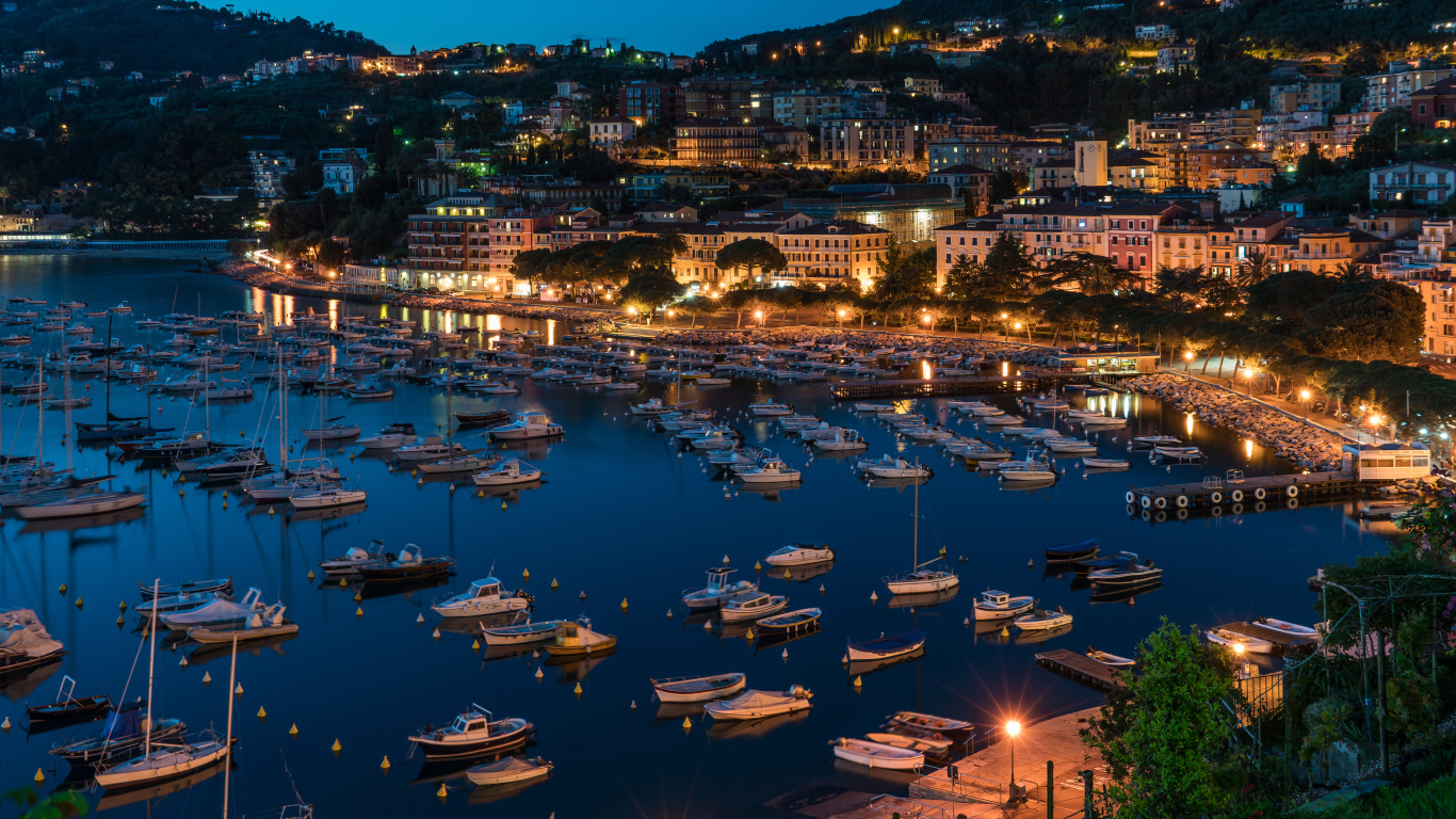 Панорама ночного города и лодки на причале у побережья, Лигурия. Италия