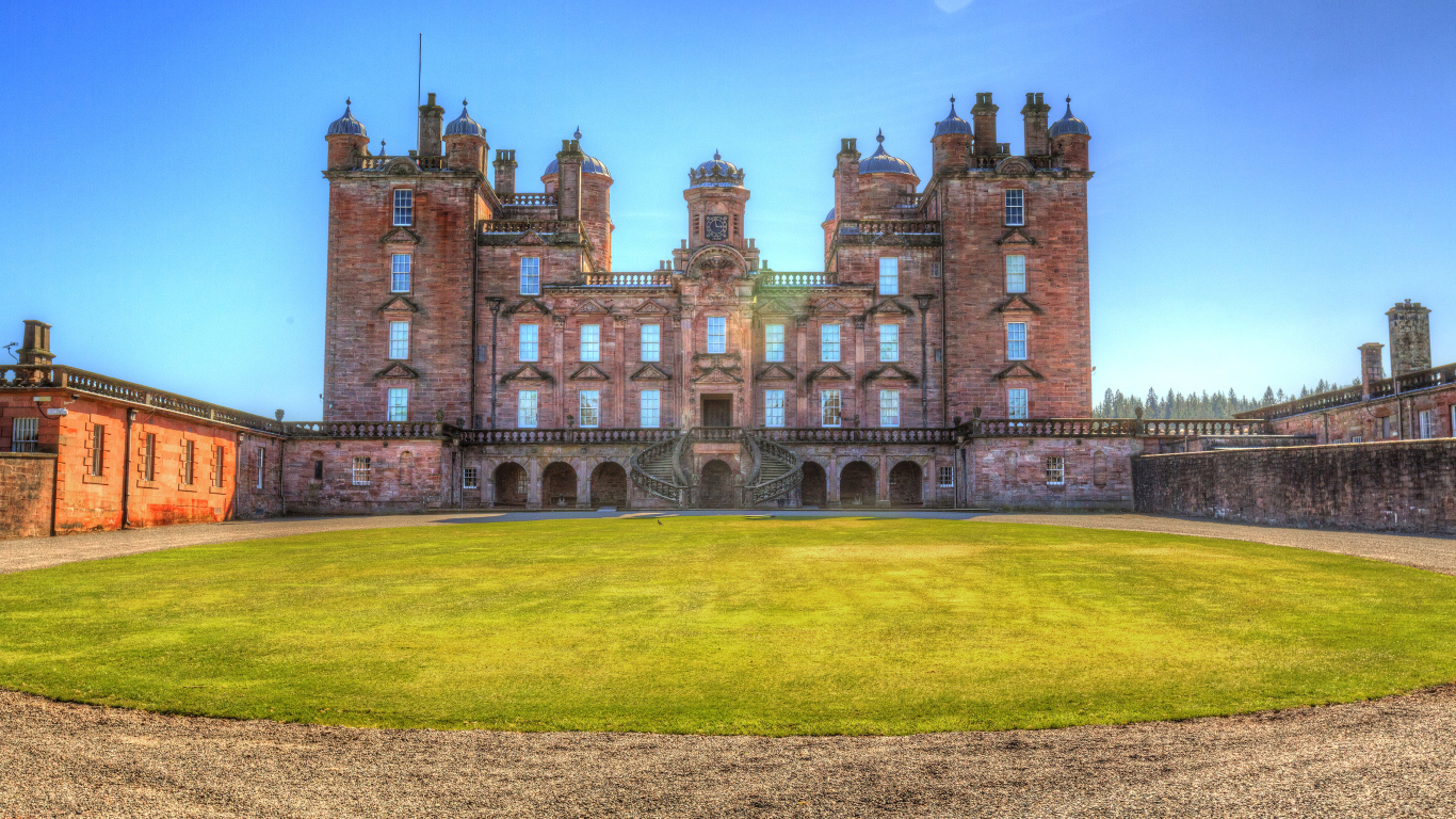 Замок Drumlanrig Castle с зеленым  газоном, Шотландия 