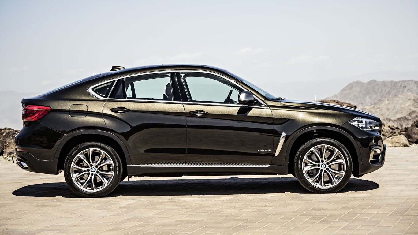 Черный автомобиль BMW X6, 2018 года вид сбоку
