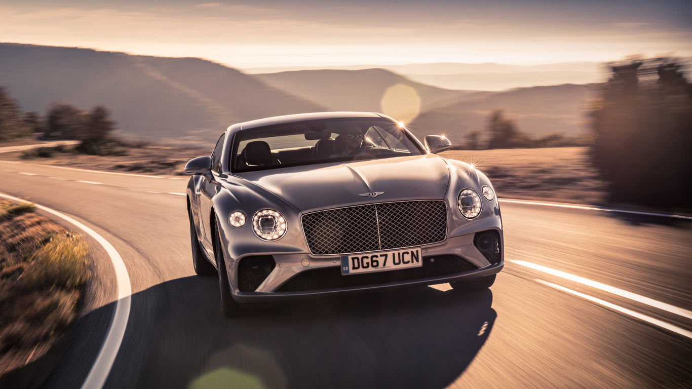 Серебристый автомобиль Bentley Continental GT 2018 года на трассе
