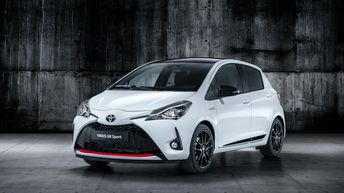 Белый автомобиль Toyota Yaris на сером фоне 