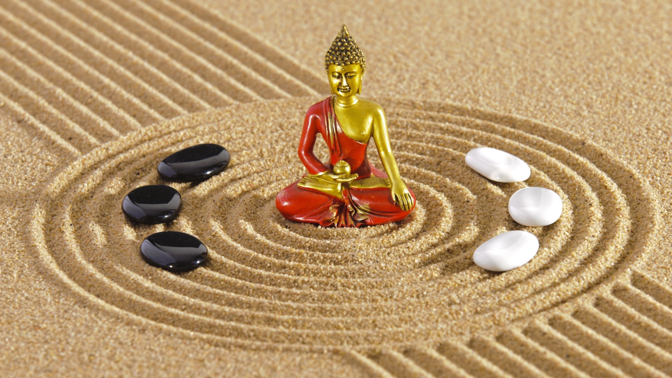 Статуэтка Будды стоит на песке с рисунком и камнями