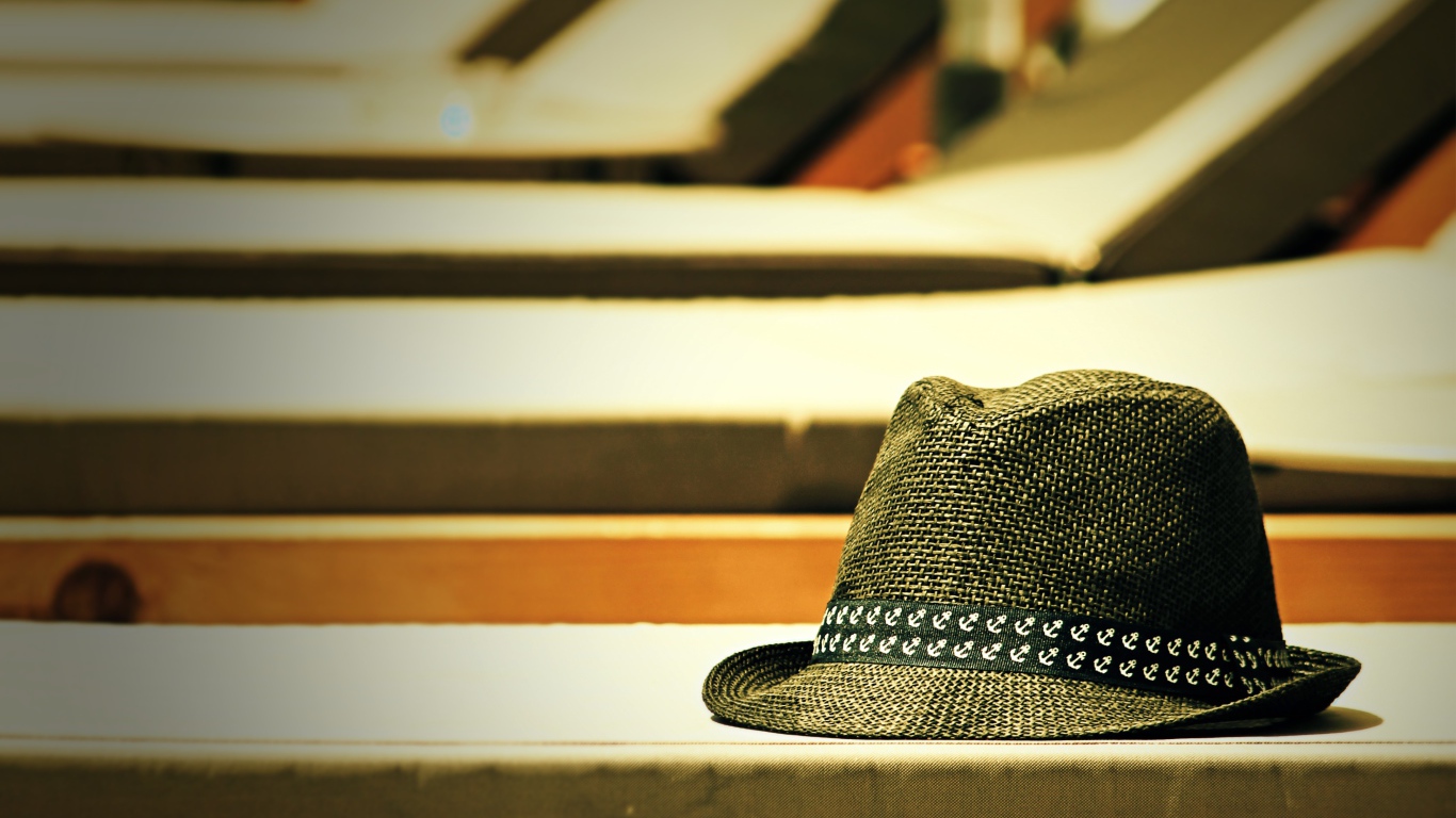 Летняя шляпа лежит на лавке в лучах солнца