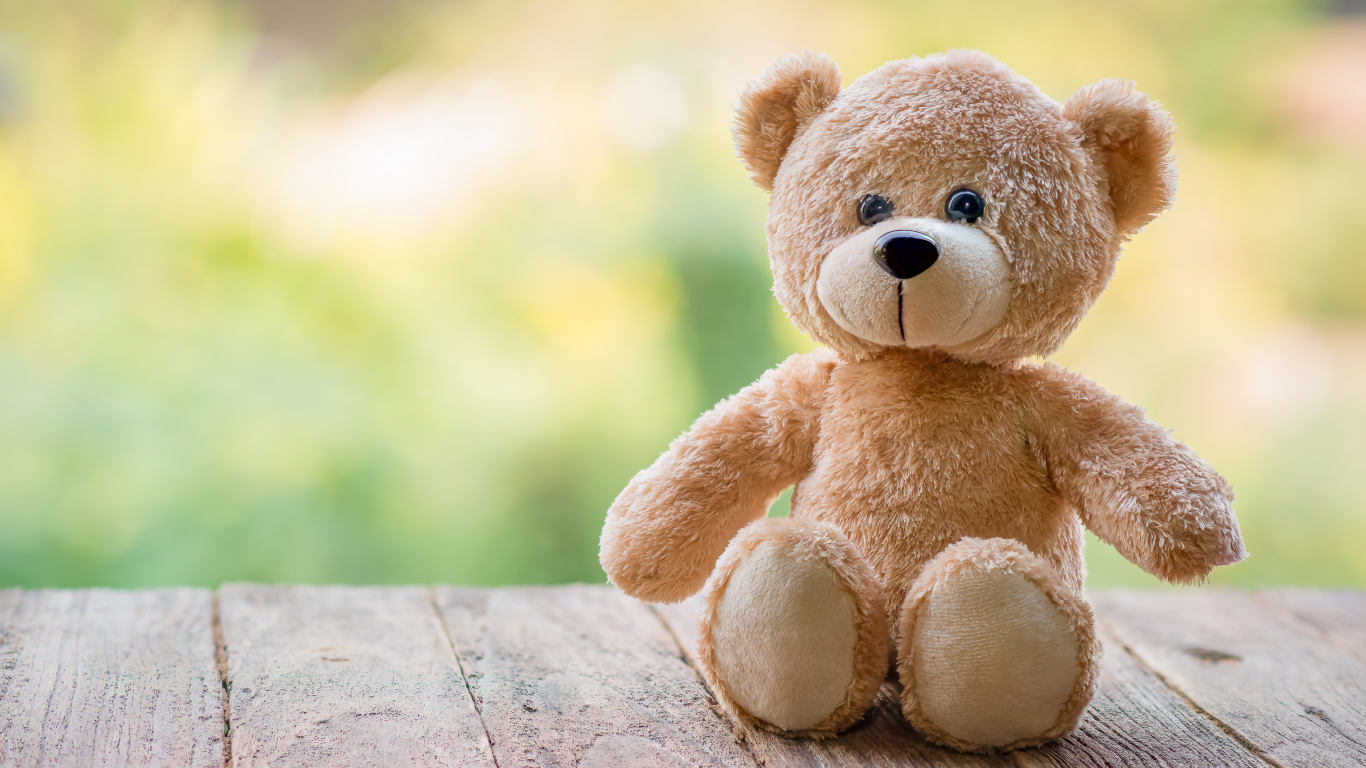 Плюшевый медведь сидит на деревянных досках