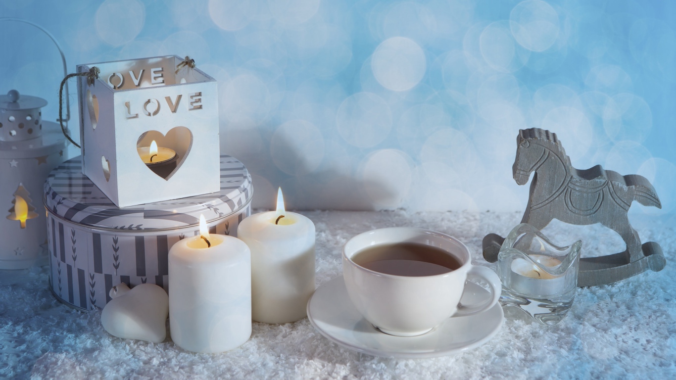 Свечи, чашка чая и фигура лошади на столе 