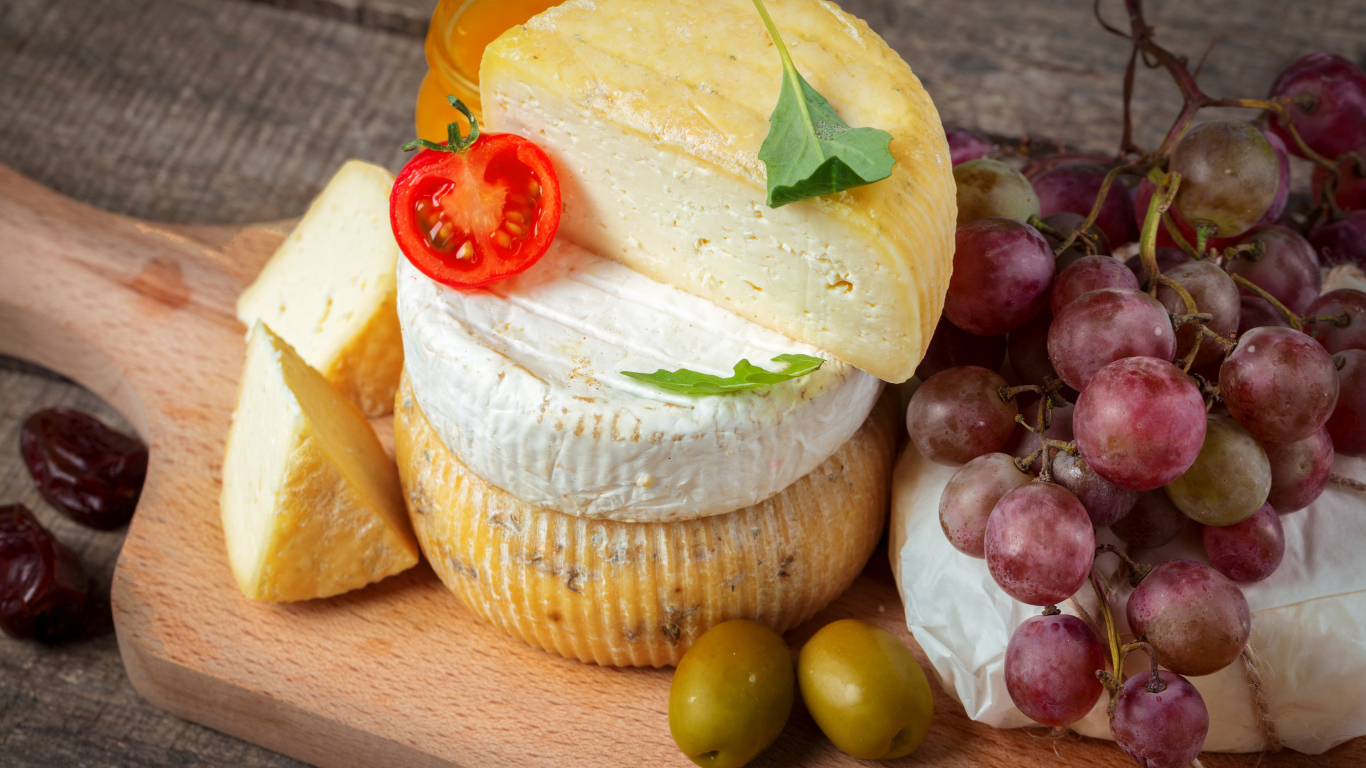 Сыр на разделочной доске с виноградом и оливками