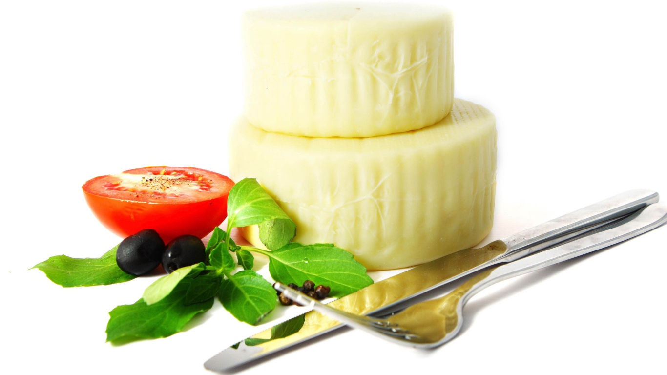 Сыр с помидором, столовыми приборами, оливками и зеленью на белом фоне