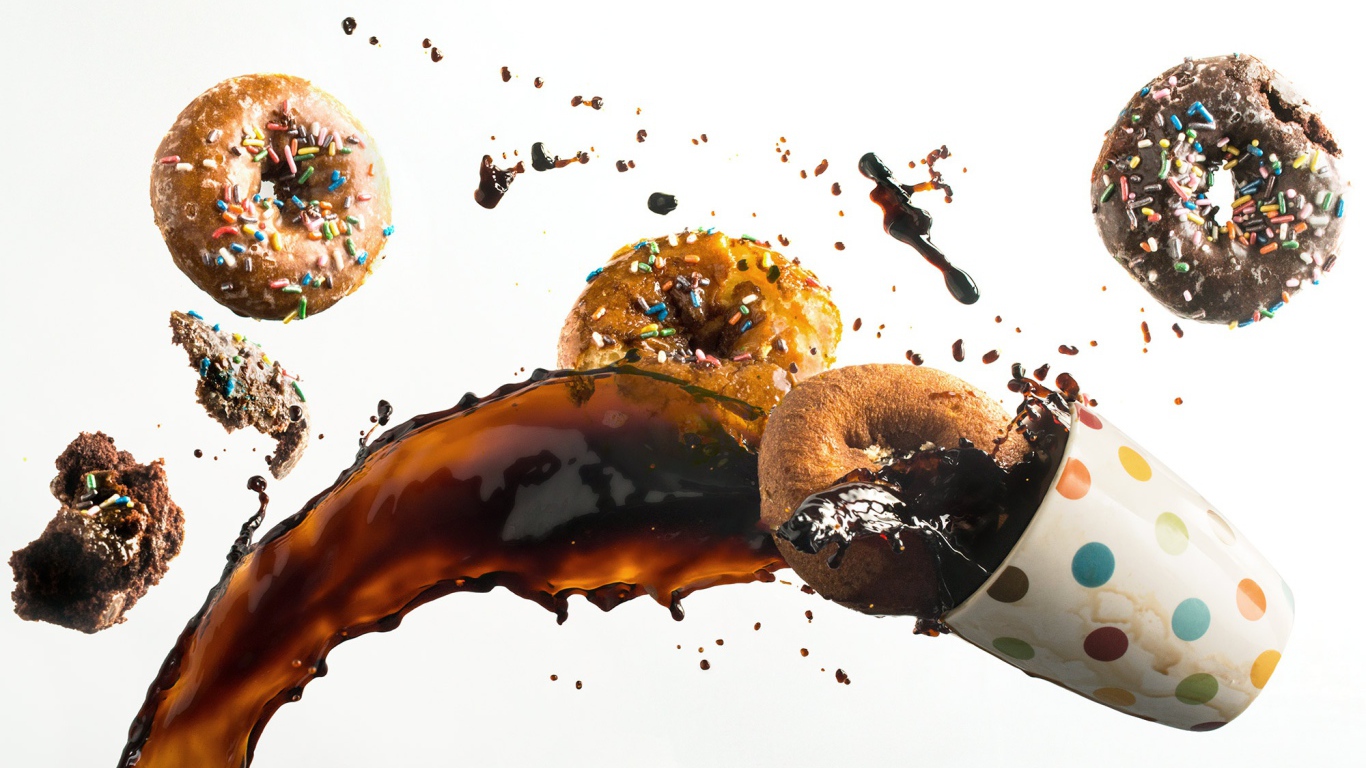 Пончики с чашкой кофе на белом фоне