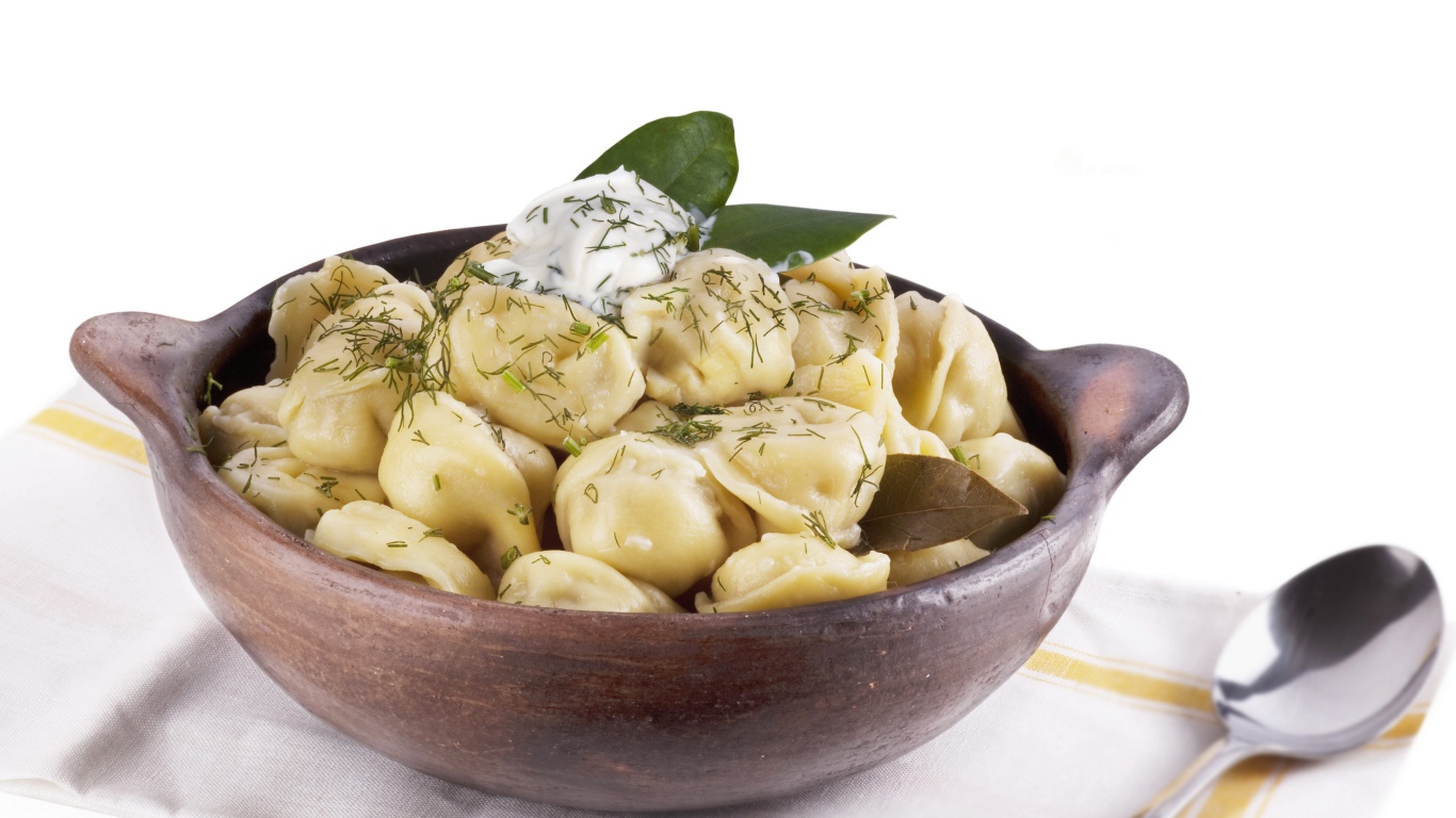 Пельмени в миске на белом фоне с ложкой 