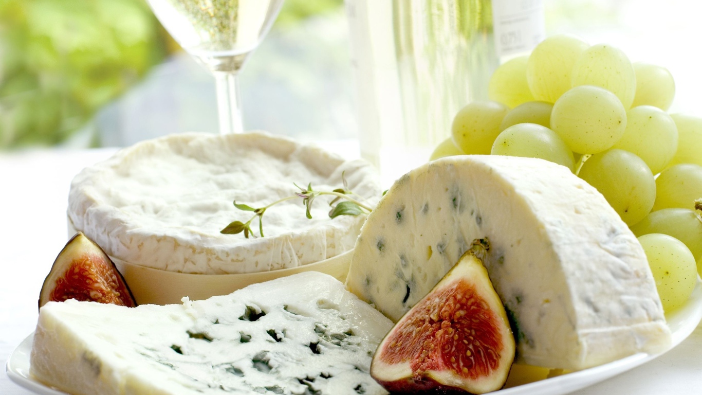 Дорогой сыр с плесенью на тарелке с инжиром и белым виноградом