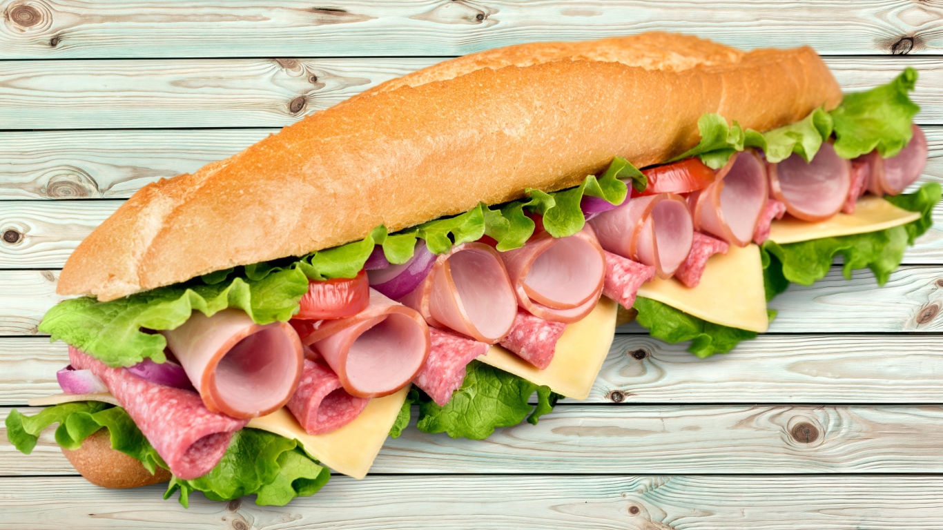 Большой бутерброд с колбасой, сыром и листьями салата