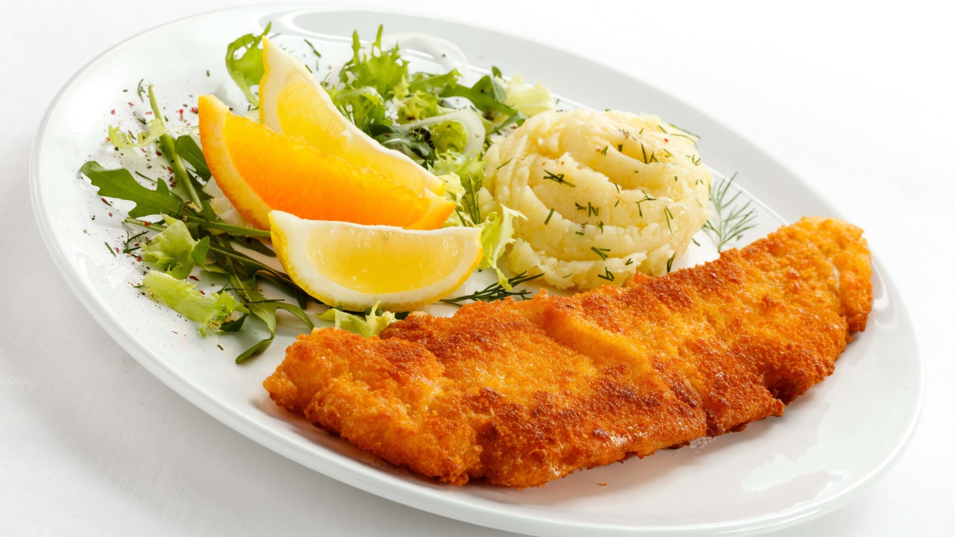 Картофельное пюре с мясом, кусочками апельсина и салатом на тарелке