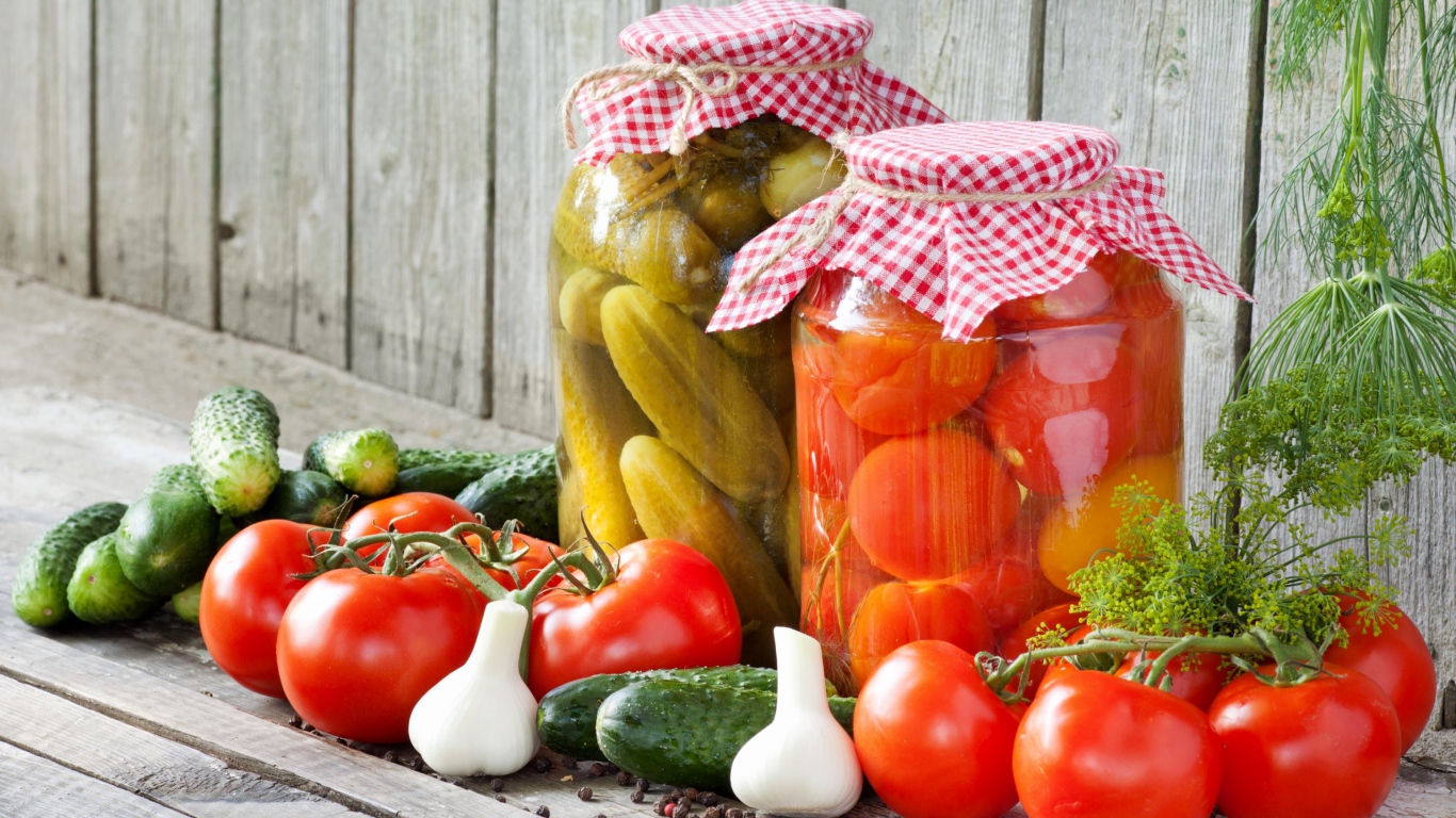 Соленья из огурцов и помидоров с овощами на столе