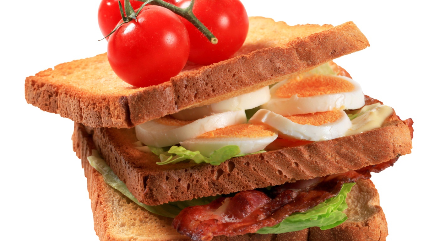 Сэндвич с яйцами, беконом и помидорами на белом фоне