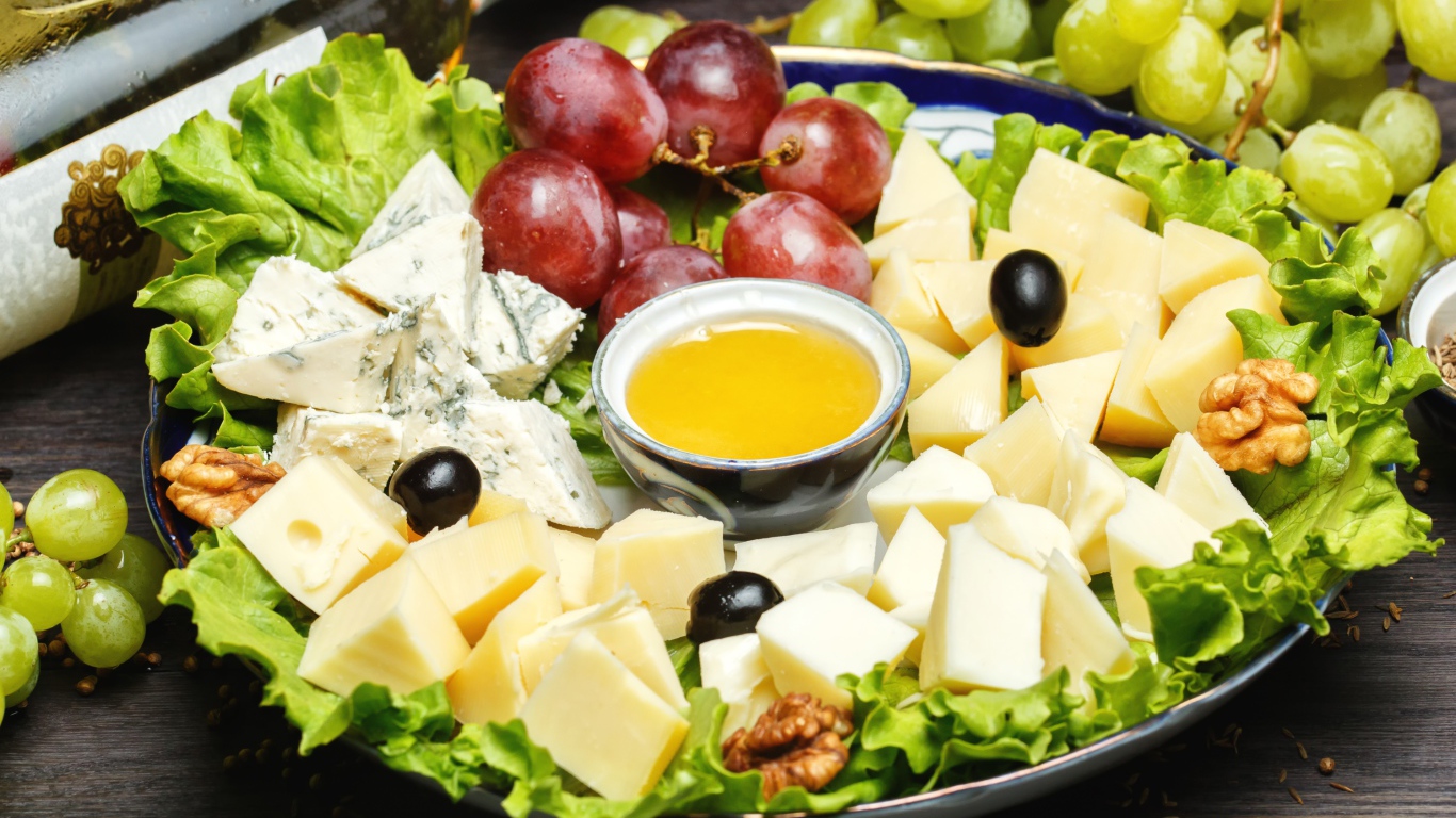 Нарезанный сыр на тарелке в виноградом 