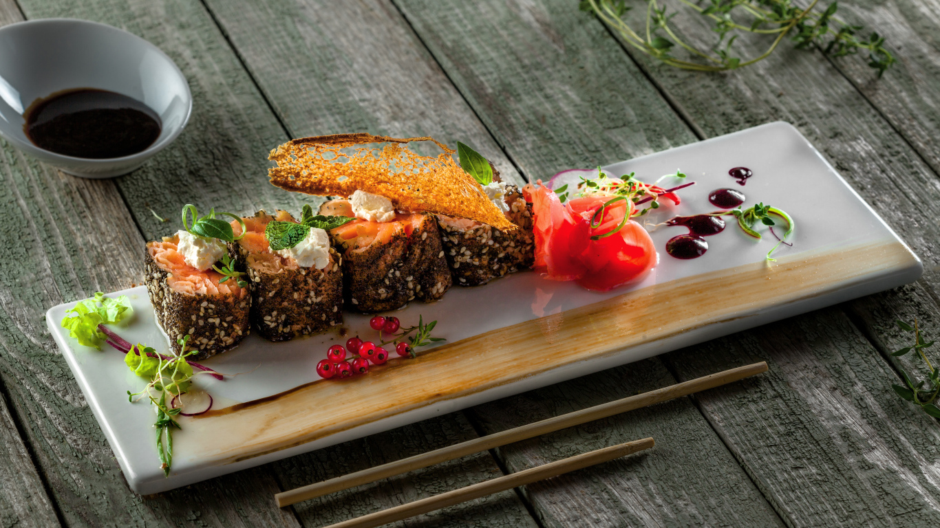 Суши на тарелке на деревянном столе с соусом