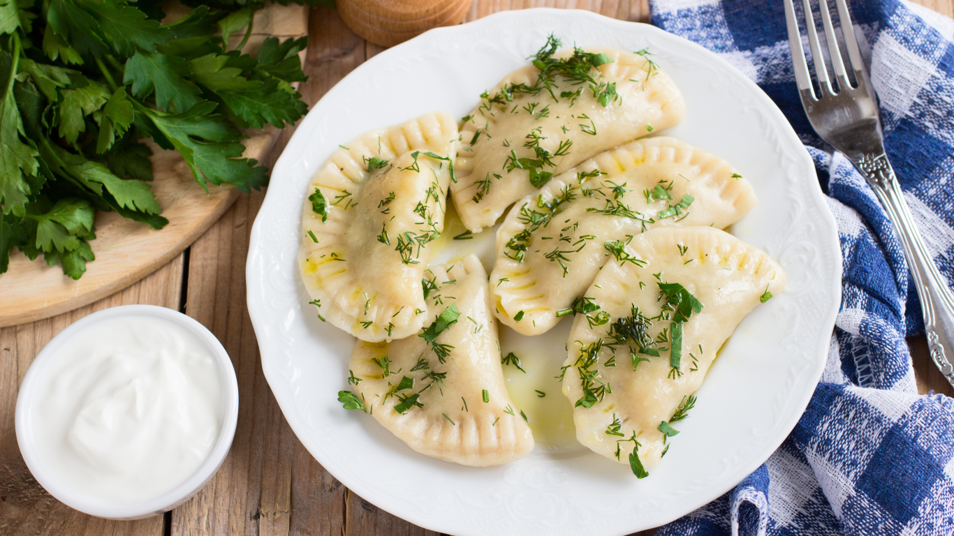 Вареники с зеленью на белой тарелке 