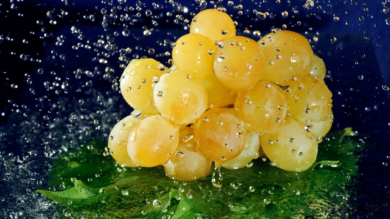 Гроздь белого винограда в брызгах воды