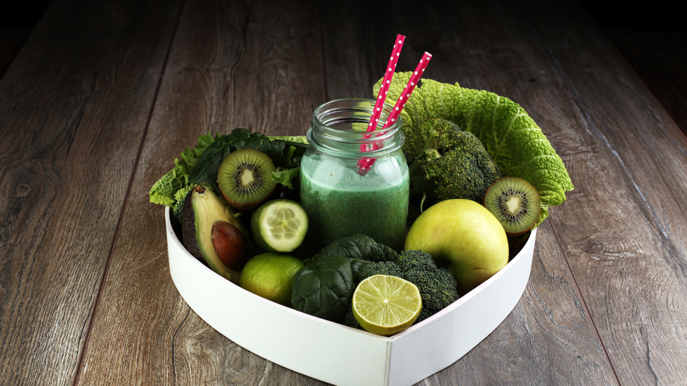 Зеленые овощи и фрукты в тарелке с баночкой смузи
